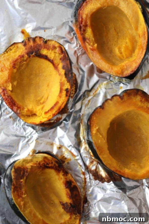 The Secret to Perfectly Roasted Squash 3 A beautifully oven-roasted acorn squash, cut in half and resting on a foil-lined baking sheet, showcasing its golden-brown edges and tender texture.