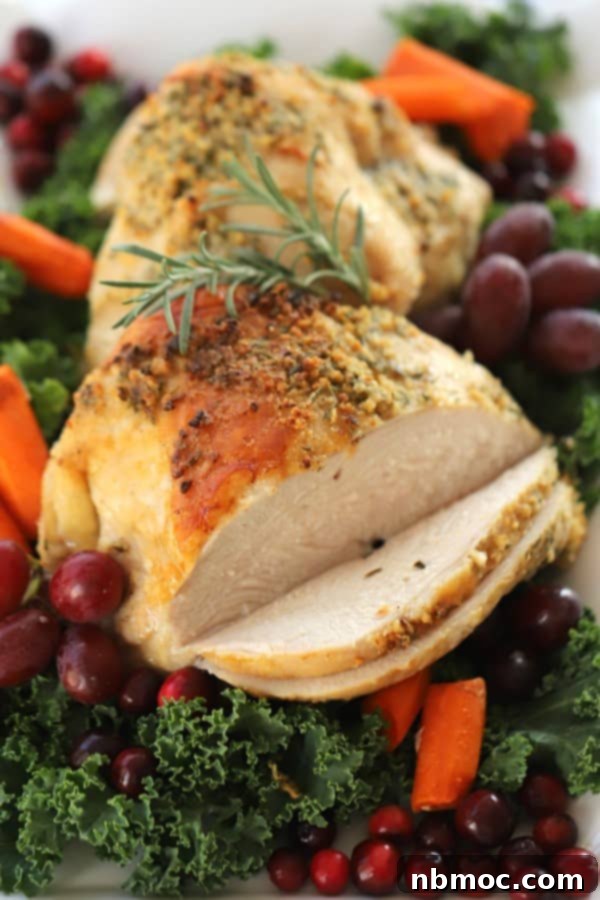 A decorative holiday platter with roasted boneless turkey breast garnished with grapes and cranberries.