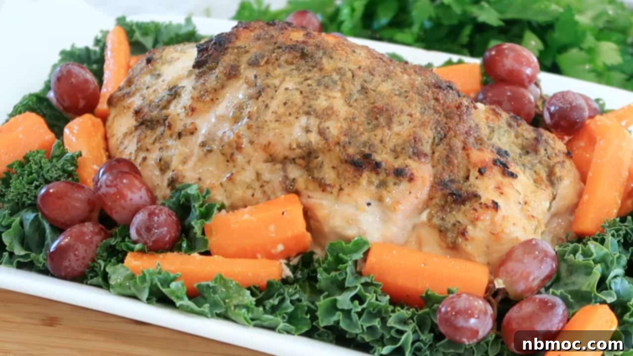 oven roasted turkey on a white platter with kale, grapes and cooked carrots