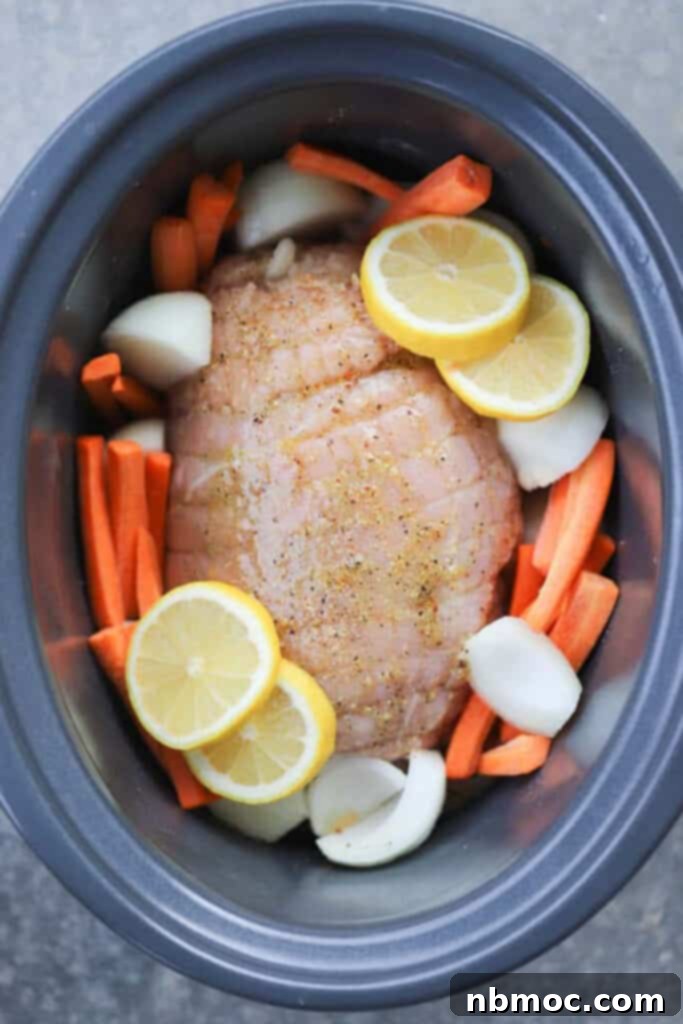 A crockpot boneless turkey breast recipe featuring lemon slices, fresh carrots, and sliced onions, all arranged and ready to slow cook to perfection.