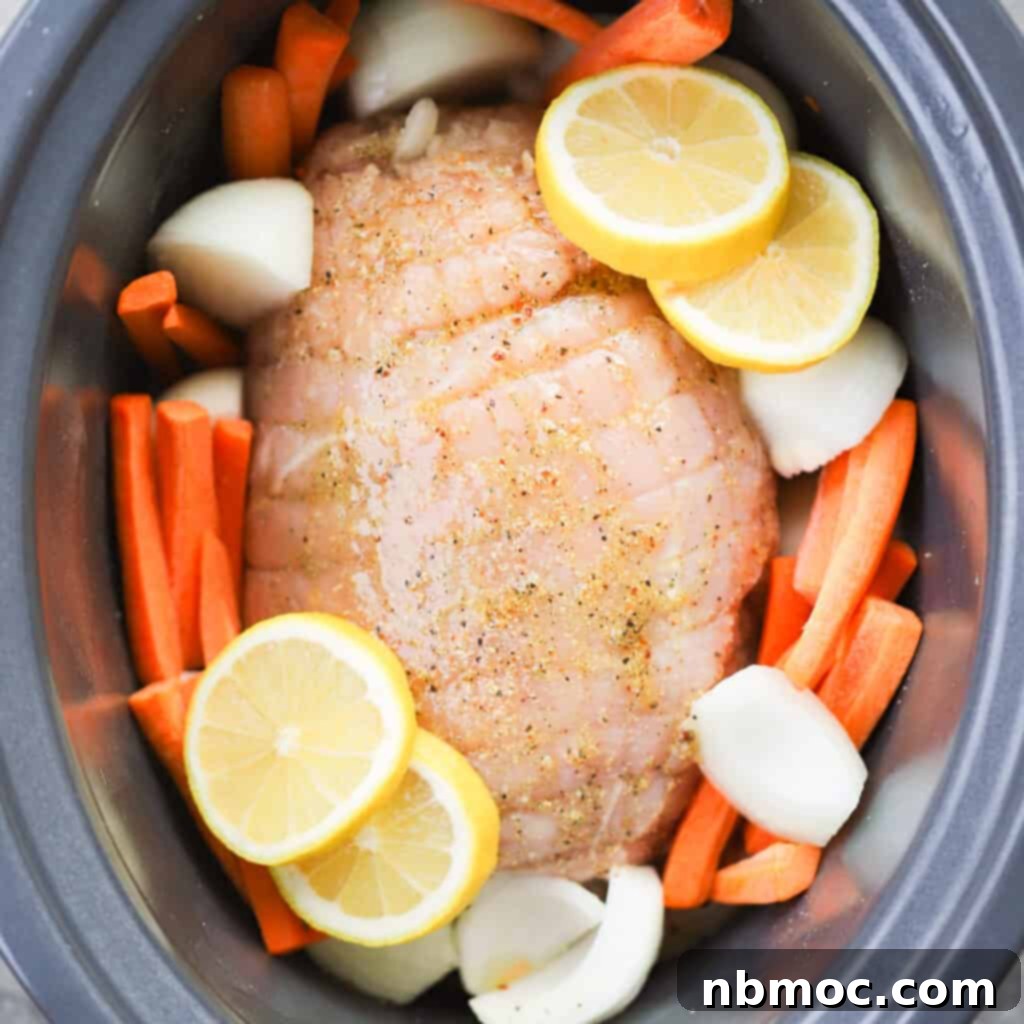 A crockpot filled with a marinated turkey breast, beautifully arranged with vibrant sliced lemons and fresh carrots, ready for slow cooking.