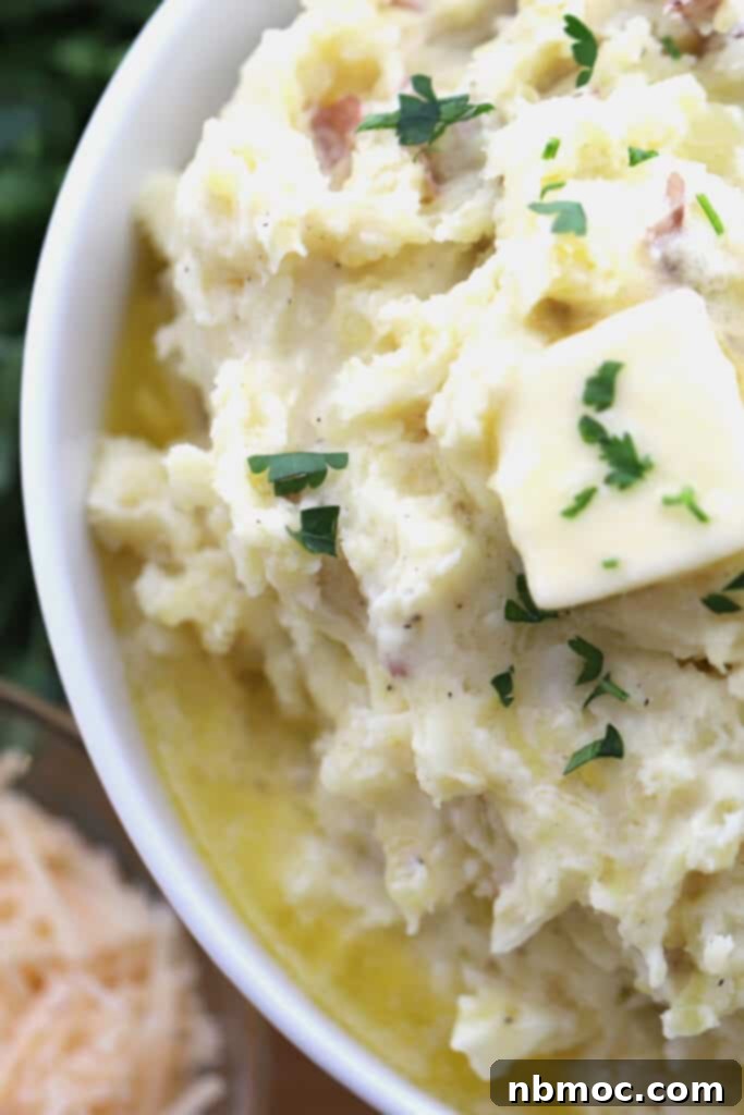 Garlic Parmesan Mashed Potatoes recipe in a bowl, generously topped with melted butter and fresh chopped parsley, ready to be served.