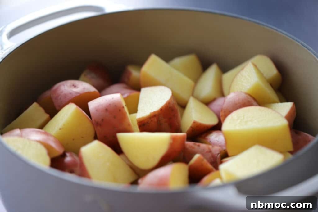 A large pot filled with expertly chopped red potatoes, ready for boiling to create a batch of delightful Parmesan mashed potatoes.
