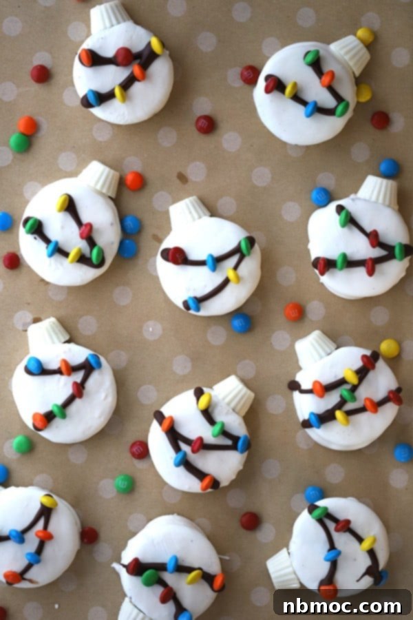 Oreos covered in white chocolate, decorated to look like Christmas ornaments with dark chocolate drizzles and colorful M&Ms, presented on a festive platter.
