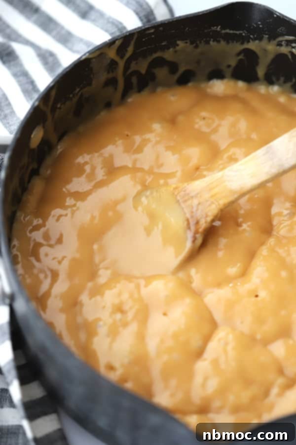 A large pot with caramel cooking, being stirred by a wooden spoon.