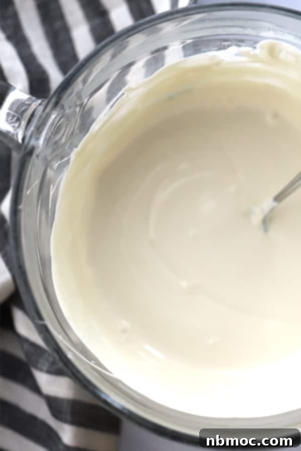 A bowl of melted white chocolate, ready for dipping Christmas caramel apples.