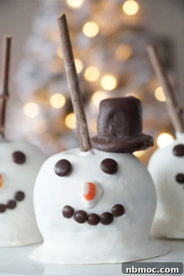 A homemade caramel apple decorated to look like a snowman, with a top hat and candy face, sitting on a textured surface.