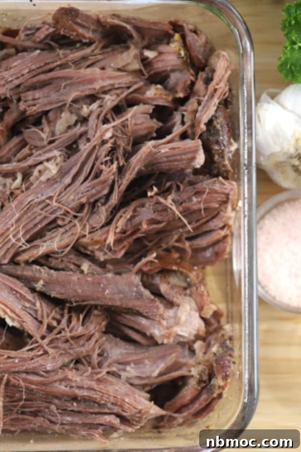 shredded slow cooker rump roast cooked to perfection and ready to serve with mashed potatoes and homemade gravy, highlighting a delicious rump roast crock pot recipe.