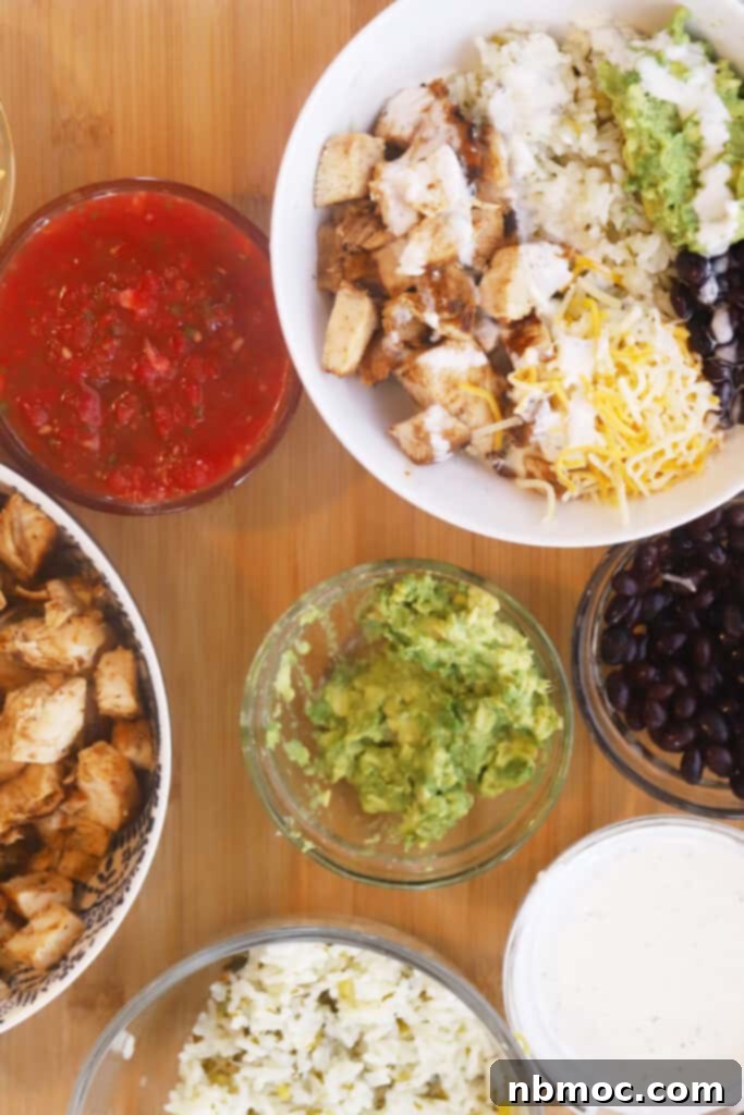 A beautifully arranged chicken burrito bowl on a rustic wooden table, surrounded by small ramekins filled with various fresh toppings, highlighting the customization options.