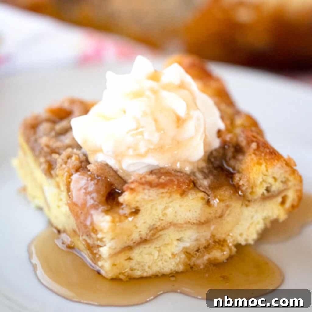 A slice of overnight french toast bake topped with syrup and whipped cream.