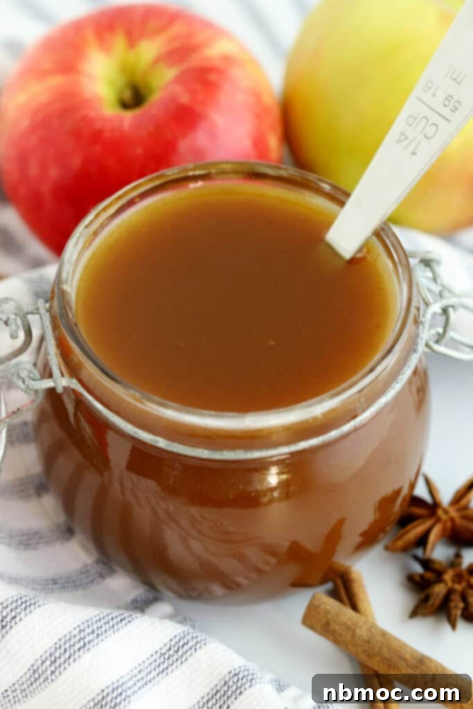 Apple Cider Syrup in a small jar with a few fresh apples around.