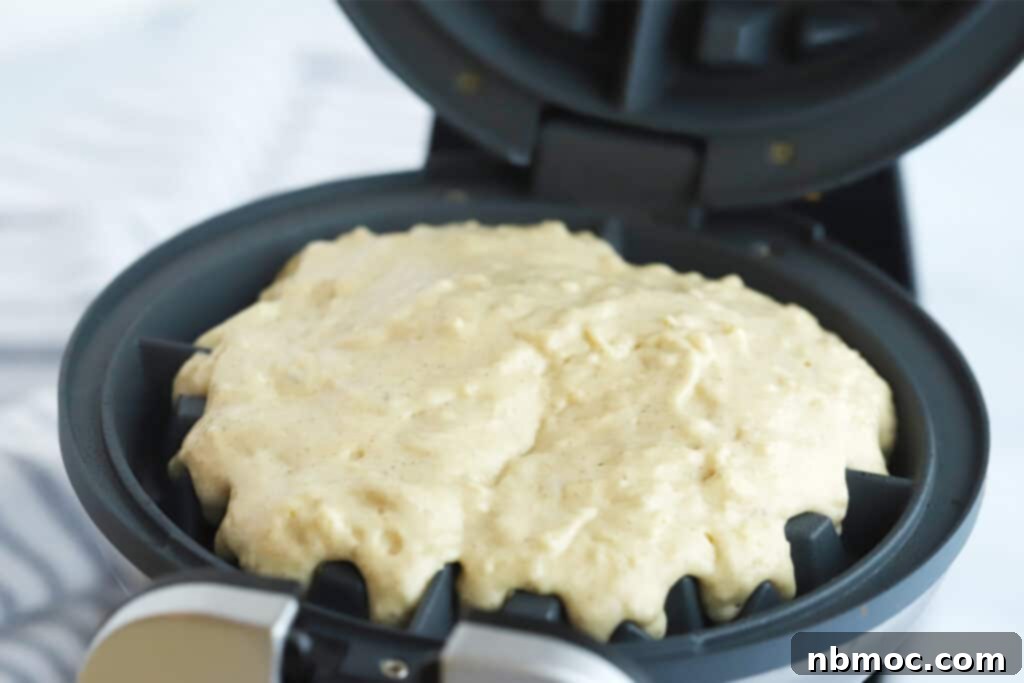 A waffle iron opened with fresh batter ready to cook, demonstrating the ease of making homemade Belgian waffles.