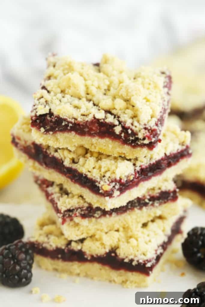 A stack of golden brown blackberry crumble bars with a thick fruit filling.