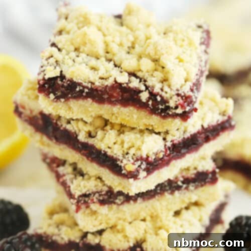 A stack of golden brown blackberry crumble bars with a thick fruit filling.