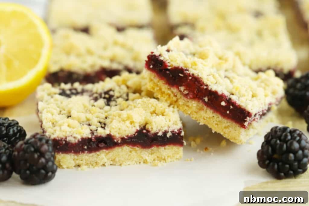 Blackberry bars with crumble topping, cut into squares, on a rustic wooden table.