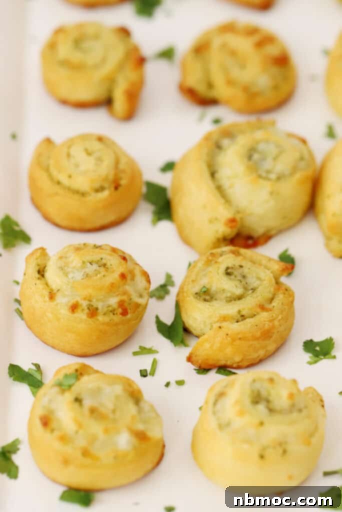 Savory Pesto Swirls 2 Pesto pinwheels garnished with fresh parsley on a serving plate, ready to be enjoyed.