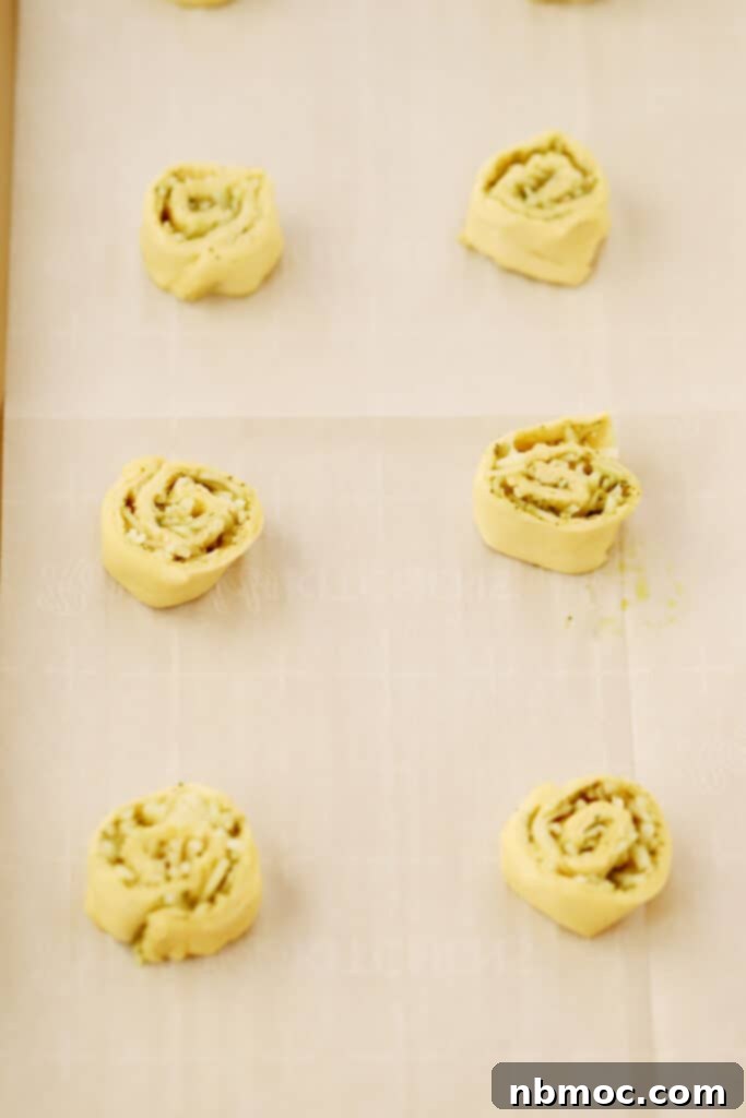 Savory Pesto Swirls 3 A tray of unbaked Pesto Pinwheels arranged on a baking sheet, ready for the oven. This shows appetizers with pesto, perfect for any occasion.