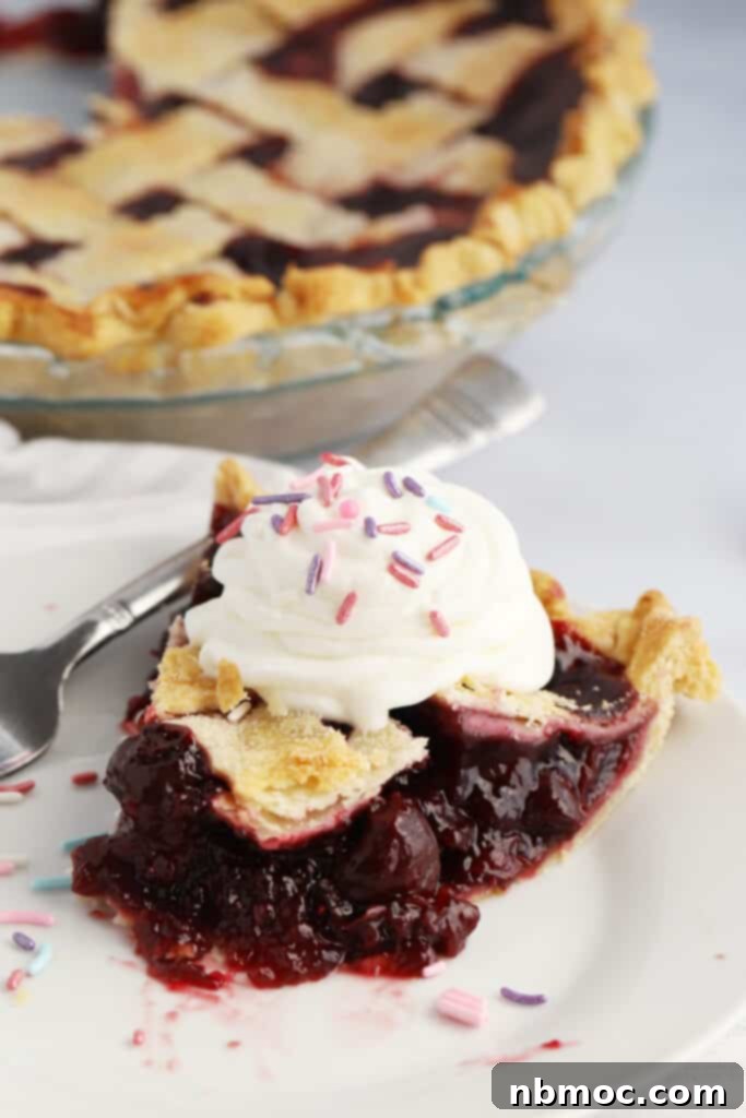 Crimson Delight 2 A plate with a slice of homemade cherry pie and a fork, with a full pie in the background, showcasing its golden, flaky crust and vibrant cherry filling.