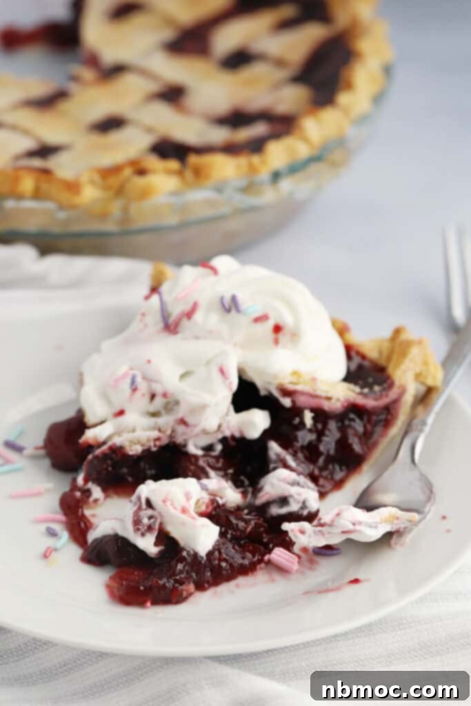 Crimson Delight 5 A perfectly baked slice of homemade cherry pie recipe, generously topped with fresh whipped cream and served on a elegant white plate with a fork, ready to be enjoyed.