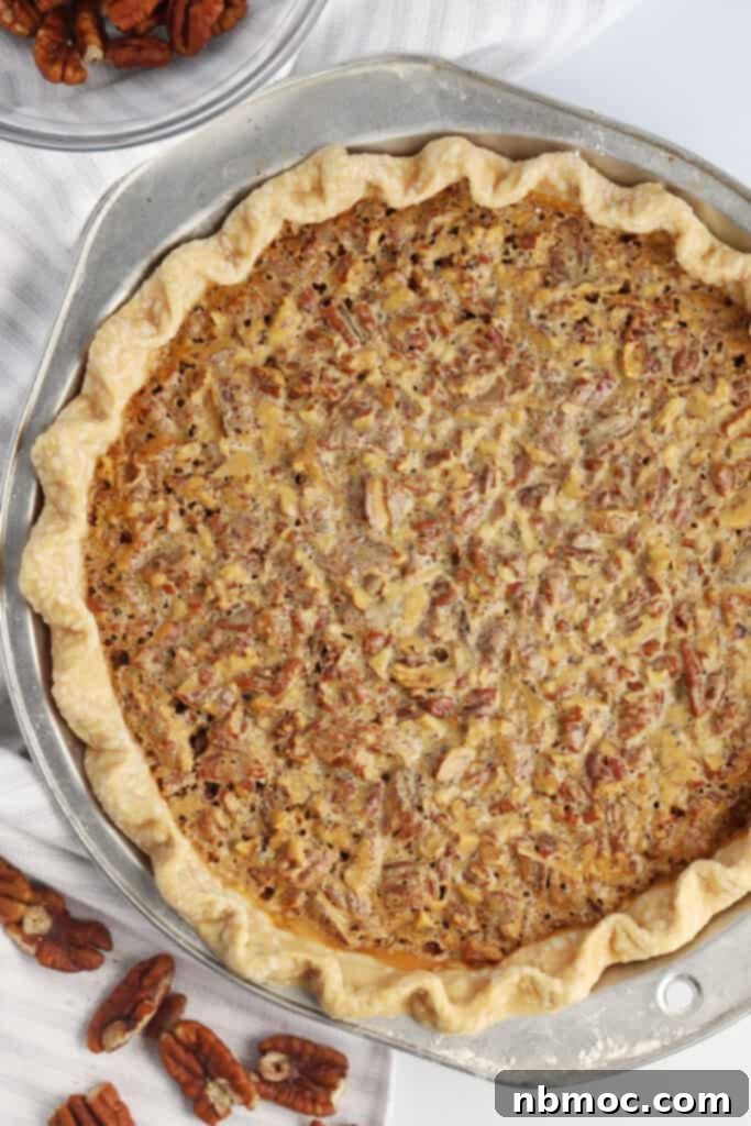 Decadent Caramel Pecan Bliss 6 The top-down view of a full homemade pecan pie in a decorative pie plate, showcasing its golden crust and nut-filled surface.
