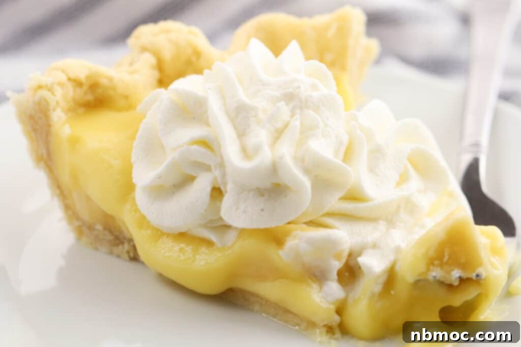 Homemade banana cream pie topped with whipped cream on a white plate. 