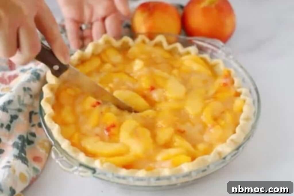cutting a fresh peach pie with a knife, chilled and ready to serve with whipped cream or ice cream. 