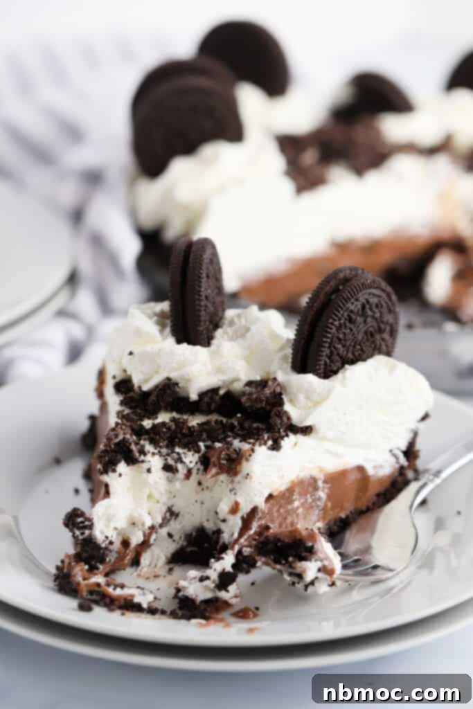 Velvety Chocolate Indulgence 6 A serving plate with a slice of chocolate cream pie topped with whipped cream and Oreo cookies.