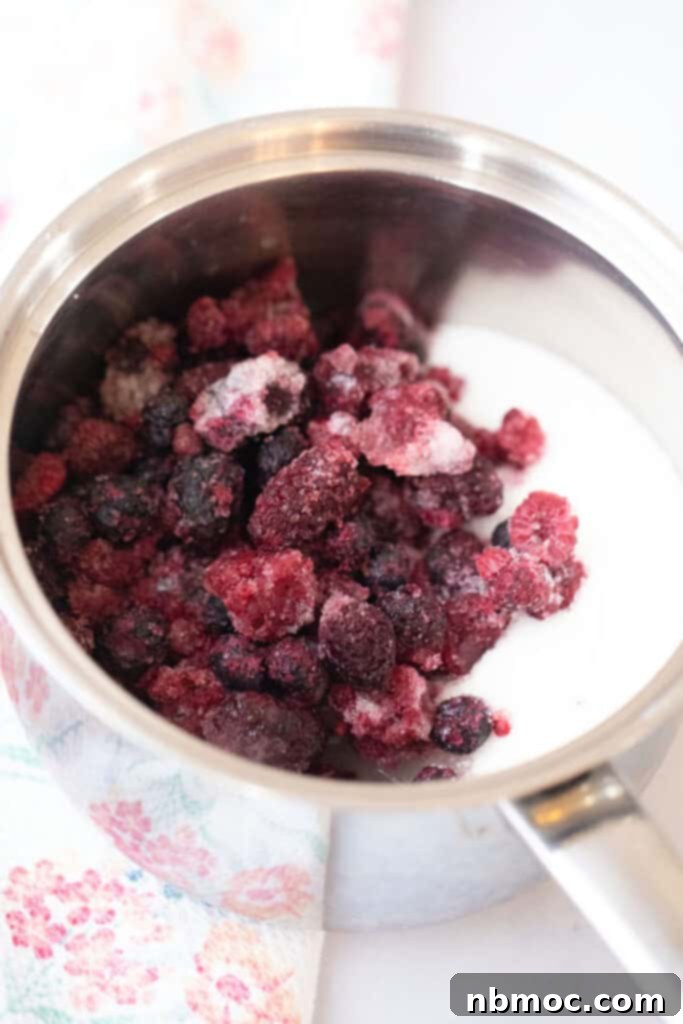 Mixed berry syrup ingredients in a saucepan, ready to be cooked on the stovetop.