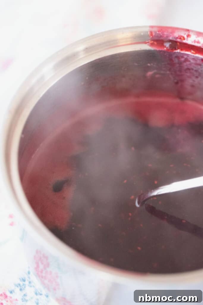 Berry syrup for pancakes bubbling in a pot on the stovetop.