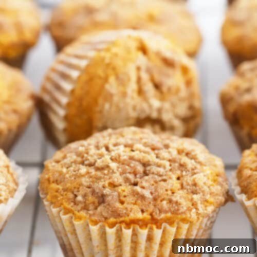 Close-up of a pumpkin cheesecake muffin with a vibrant cream cheese swirl on top.