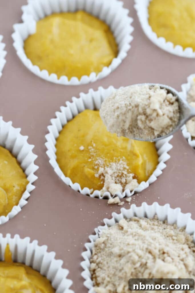 Muffin tins with pumpkin batter, ready for streusel topping to be applied.