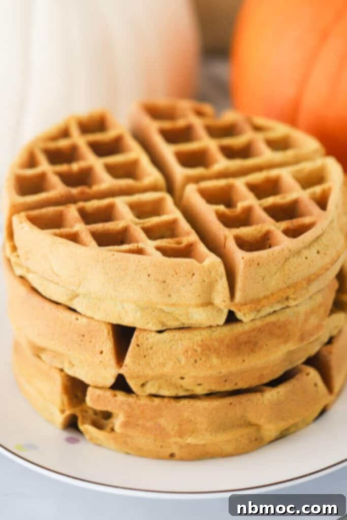 Pumpkin waffles stacked on a plate.