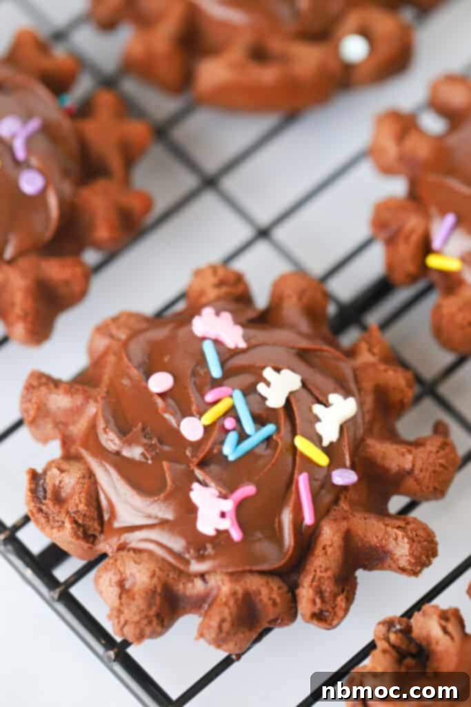 Waffled Brownie Delights 2 A cooling rack with chocolate waffle cookies topped with chocolate frosting and sprinkles.