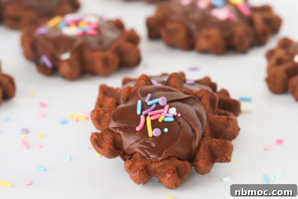 Waffled Brownie Delights 3 Waffle brownie cookies on a table topped with chocolate frosting and sprinkles.