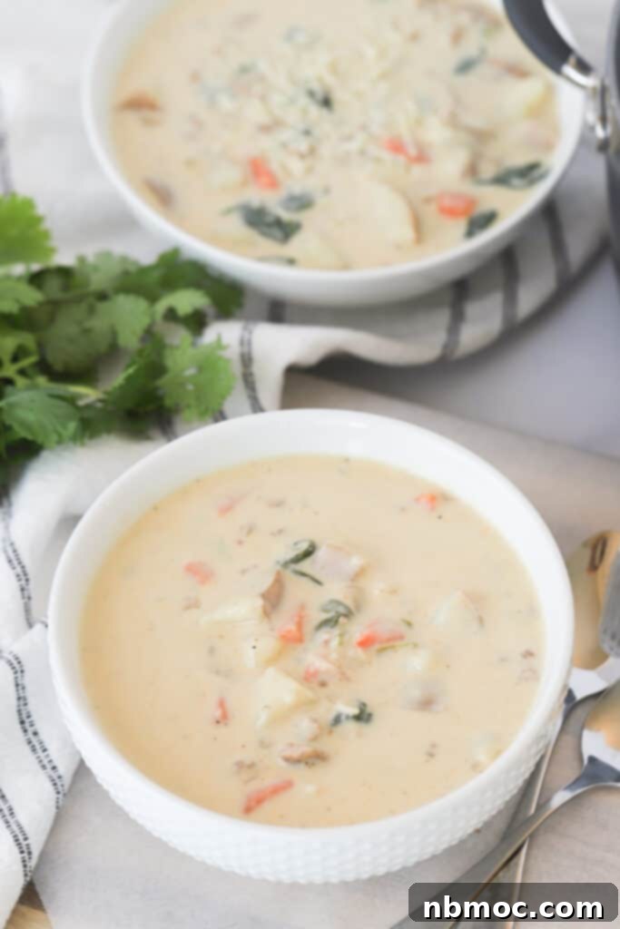 A steaming bowl of authentic Tuscan Soup with sausage, potatoes, carrots, and spinach, resembling the classic Olive Garden Zuppa Toscana.