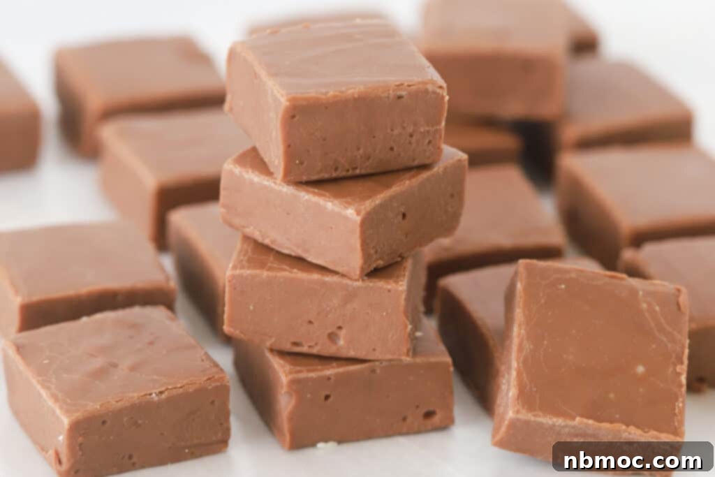 A close-up shot of multiple pieces of rich chocolate fudge stacked artfully on a kitchen countertop.