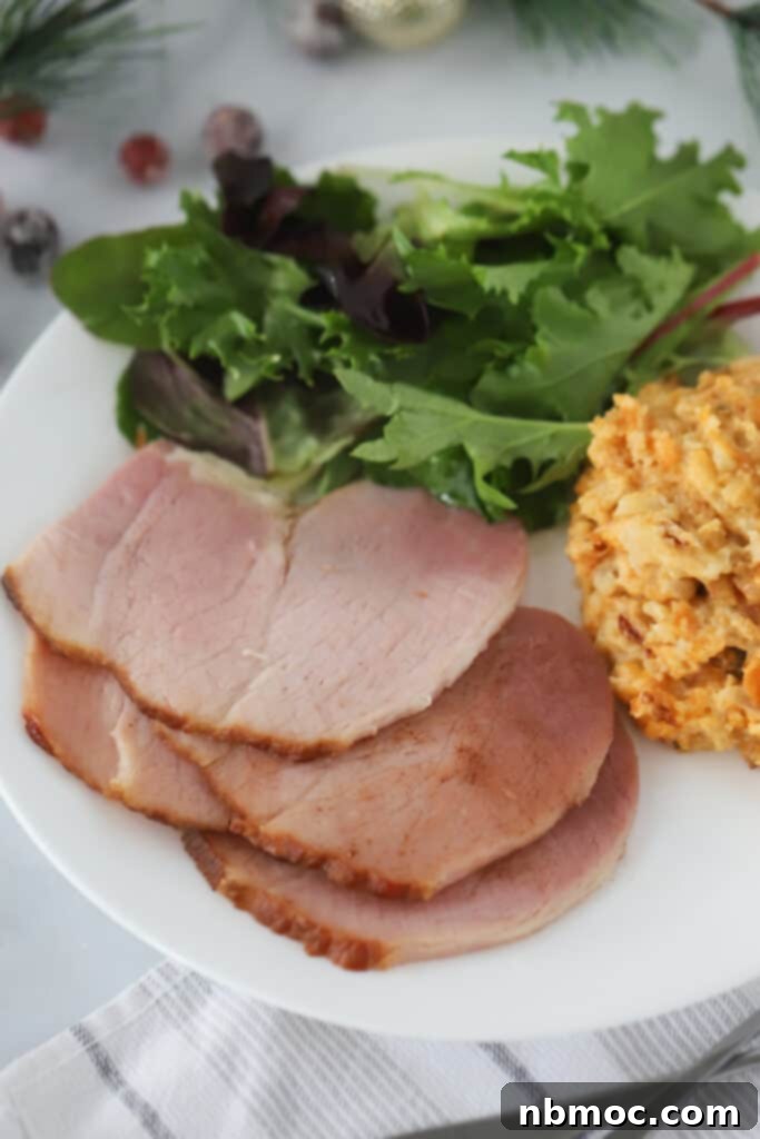 A perfectly cooked spiral sliced ham recipe, elegantly plated with fresh salad and creamy mac and cheese, ready for a festive dinner.