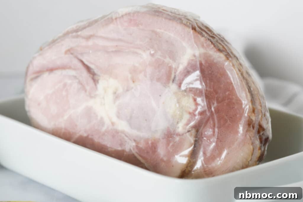 A pre-cooked spiral ham, still in its original packaging, carefully placed inside a baking dish, ready for preparation.