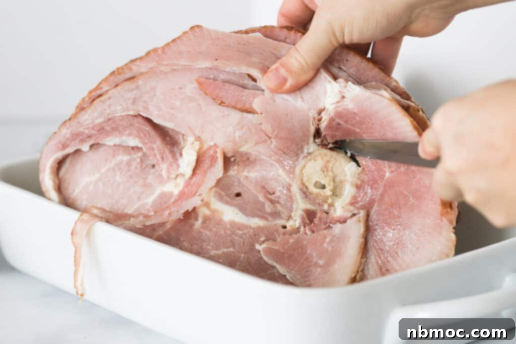 Expertly slicing a spiral ham directly inside a baking dish after it's been cooked and glazed.