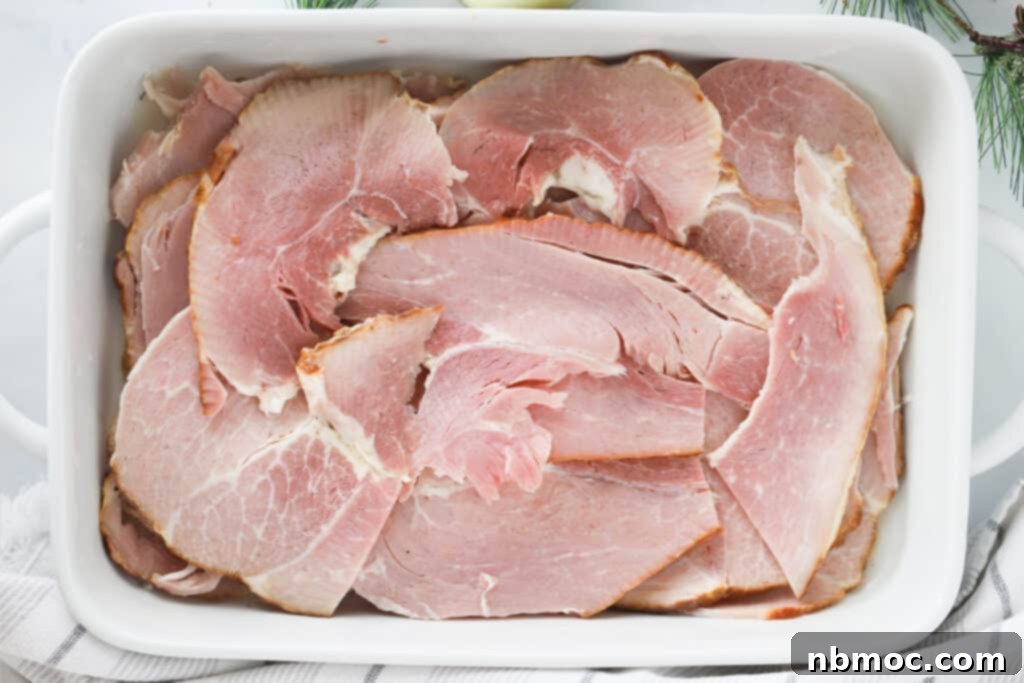 A spiral cut ham perfectly cooked and presented in a white ceramic baking dish, ready to be carved and served.