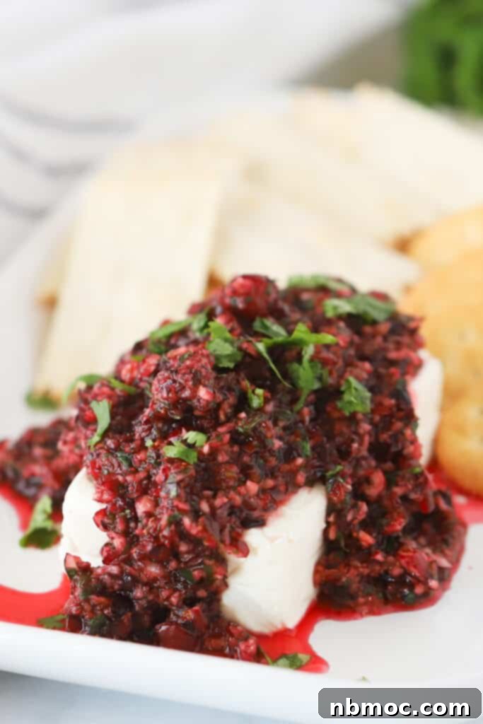 Cranberry Salsa over cream cheese on a plate with crackers.