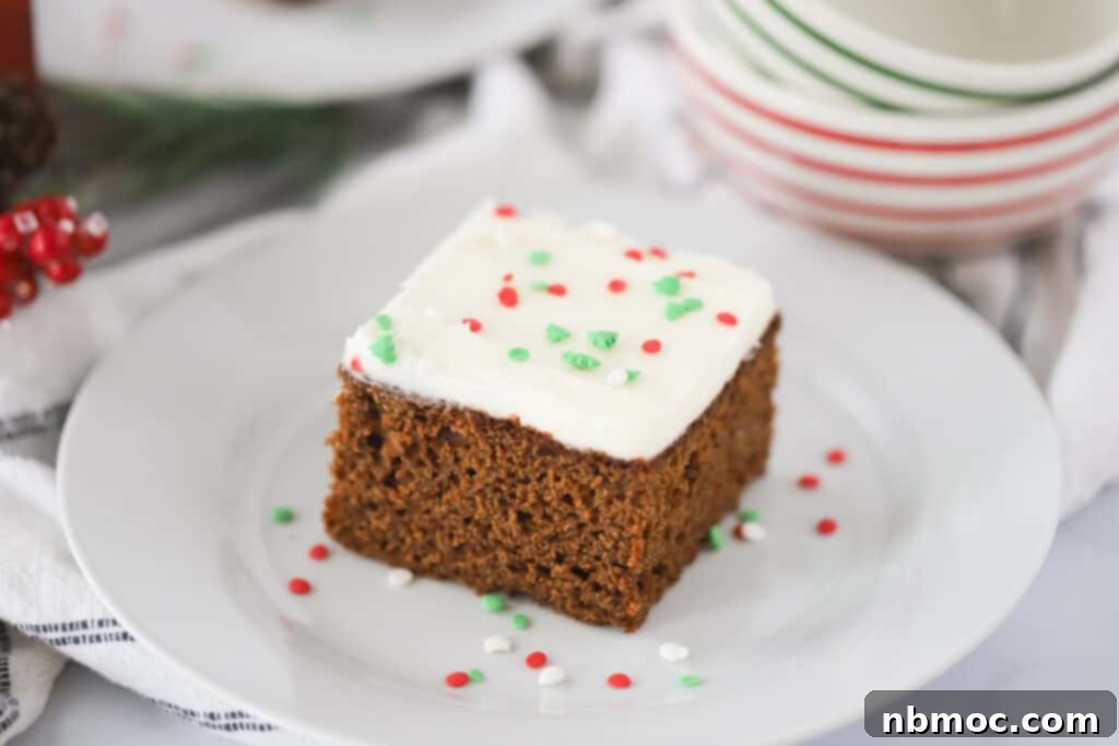 Aromatic Ginger Spice Bake 4 A festive slice of easy gingerbread cake, beautifully topped with creamy frosting and colorful holiday sprinkles, resting on a white plate.