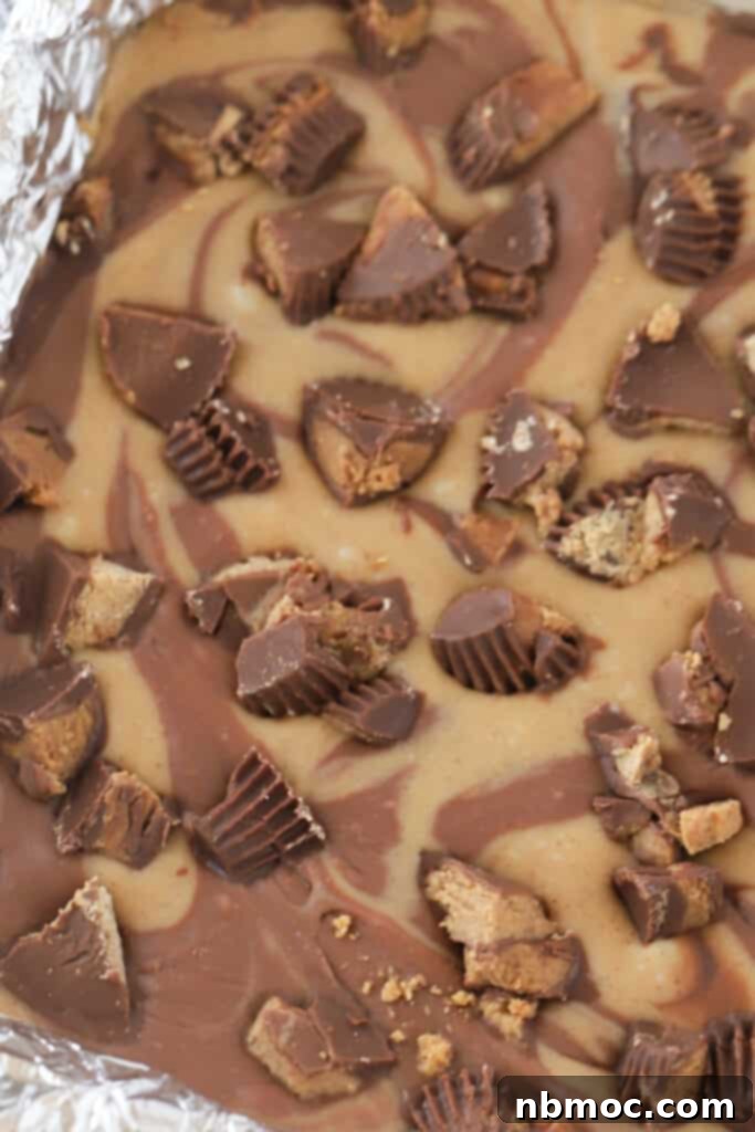 Reese's peanut butter fudge in a baking dish lined with foil, ready to be cut.