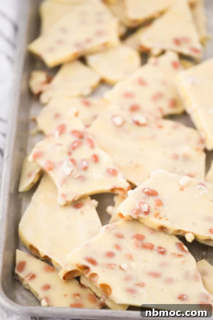 An old-fashioned peanut brittle recipe broken into pieces and laying on a baking sheet.
