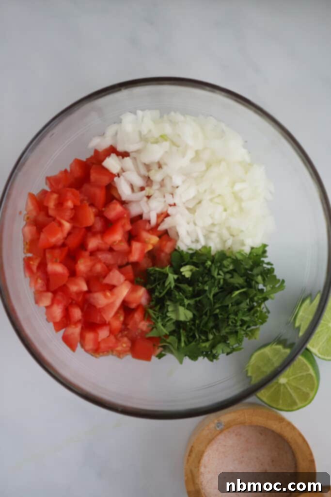 A glass bowl with ingredients to make this traditional pico de gallo recipe.