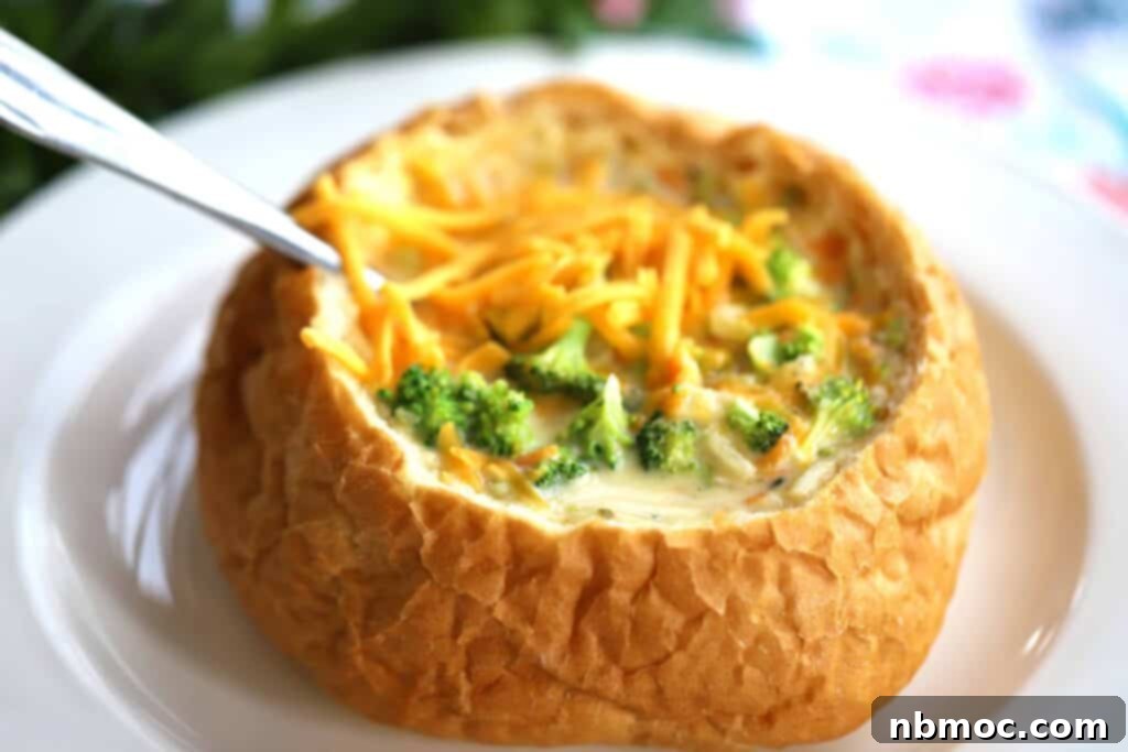 Hearty Potato Broccoli Cheese Soup served in a rustic bread bowl with a spoon, garnished with fresh herbs.