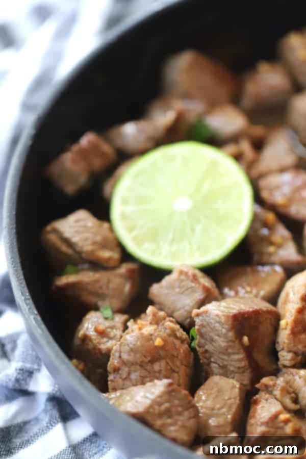 A saute pan with steak cubes sauteed and cooked to make this garlic steak bites recipe.
