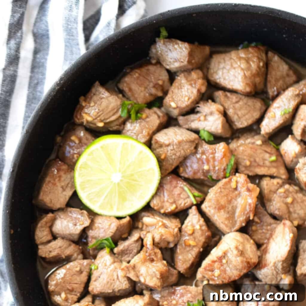 Honey garlic steak bites in a cast iron skillet with a fresh lime.