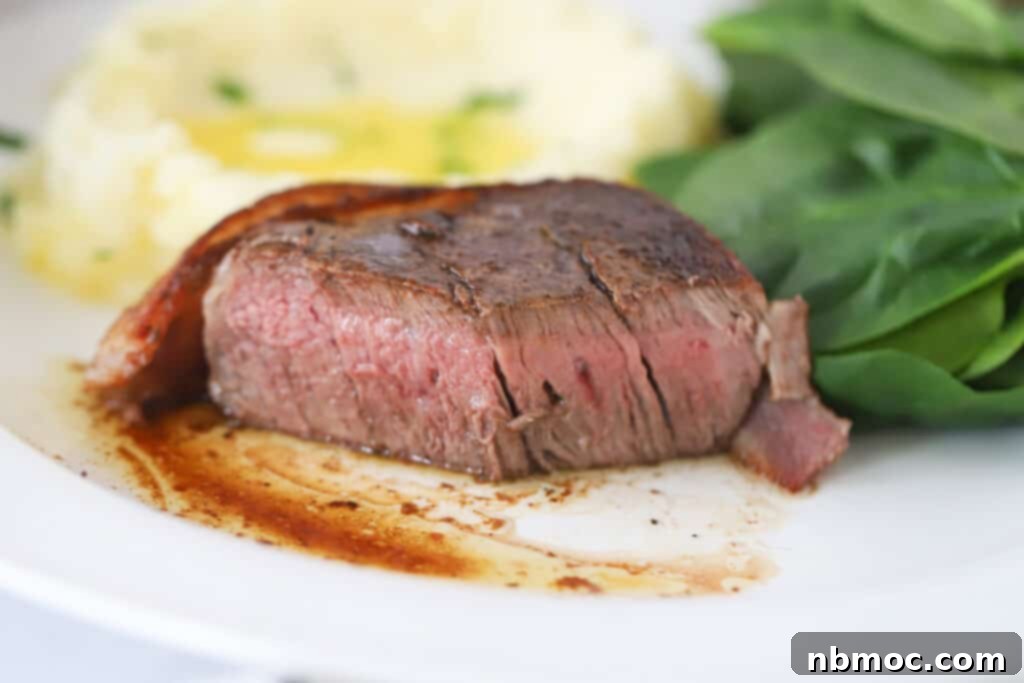 A pristine piece of raw filet mignon steak, expertly wrapped in a slice of bacon and secured with a toothpick, poised for cooking. This image illustrates how to make bacon wrapped filet mignon and homemade steak recipe preparation.