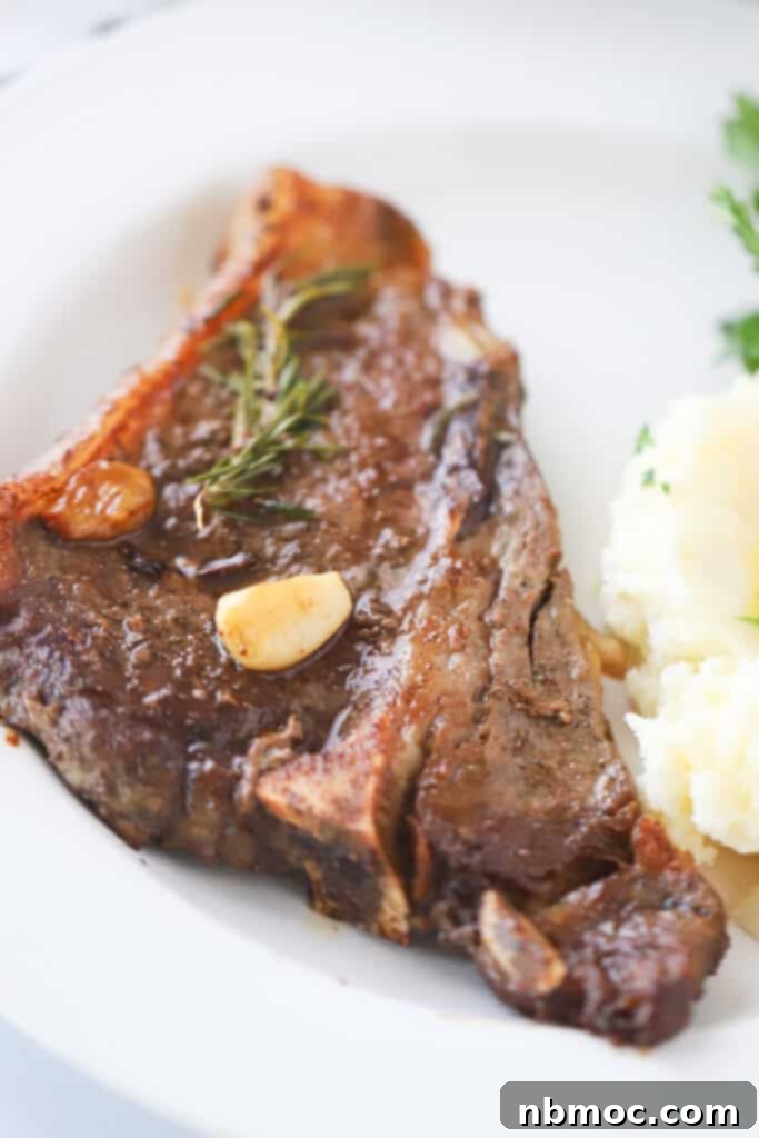 A dinner plate with a Pan Seared Steak finished in oven with a side of potatoes, showcasing the perfectly cooked exterior.